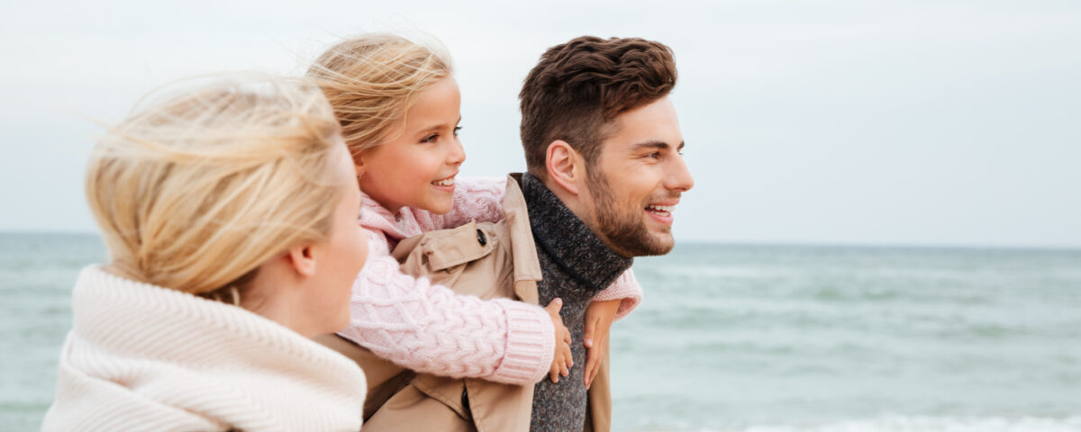 Famiglia sorridente sulla spiaggia con bambini e genitori.