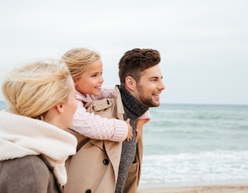 Famiglia sorridente sulla spiaggia con bambini e genitori.